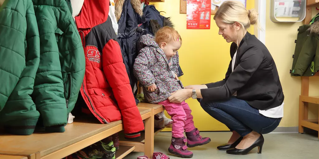 Eine Frau kniet vor einem Kind 