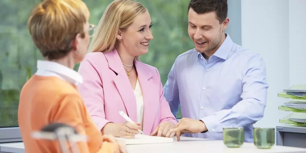 Drei Personen unterhalten sich an einem Stehtisch