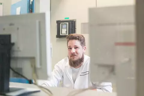 Mann mit Bart am Computer vor zwei Bildschirmen