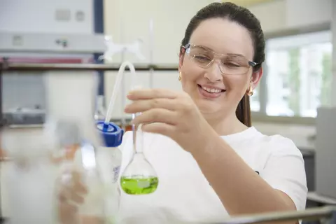 Ein Wissenschaftlerin füllt Flüssigkeit in ein Reagenzglas
